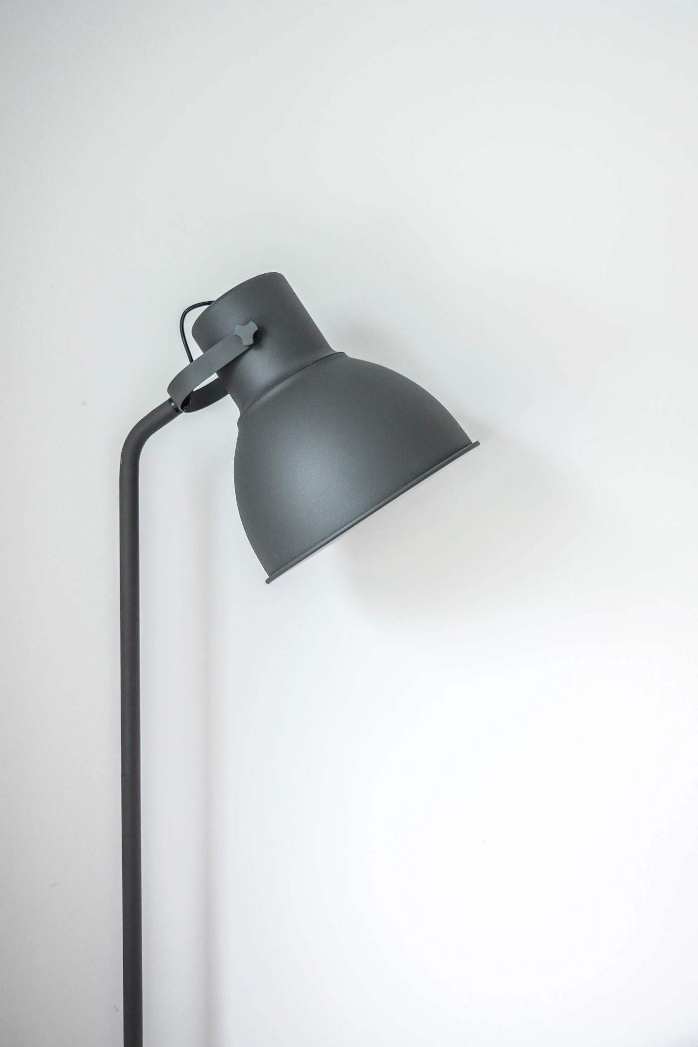 Black adjustable task lamp against a pale wall