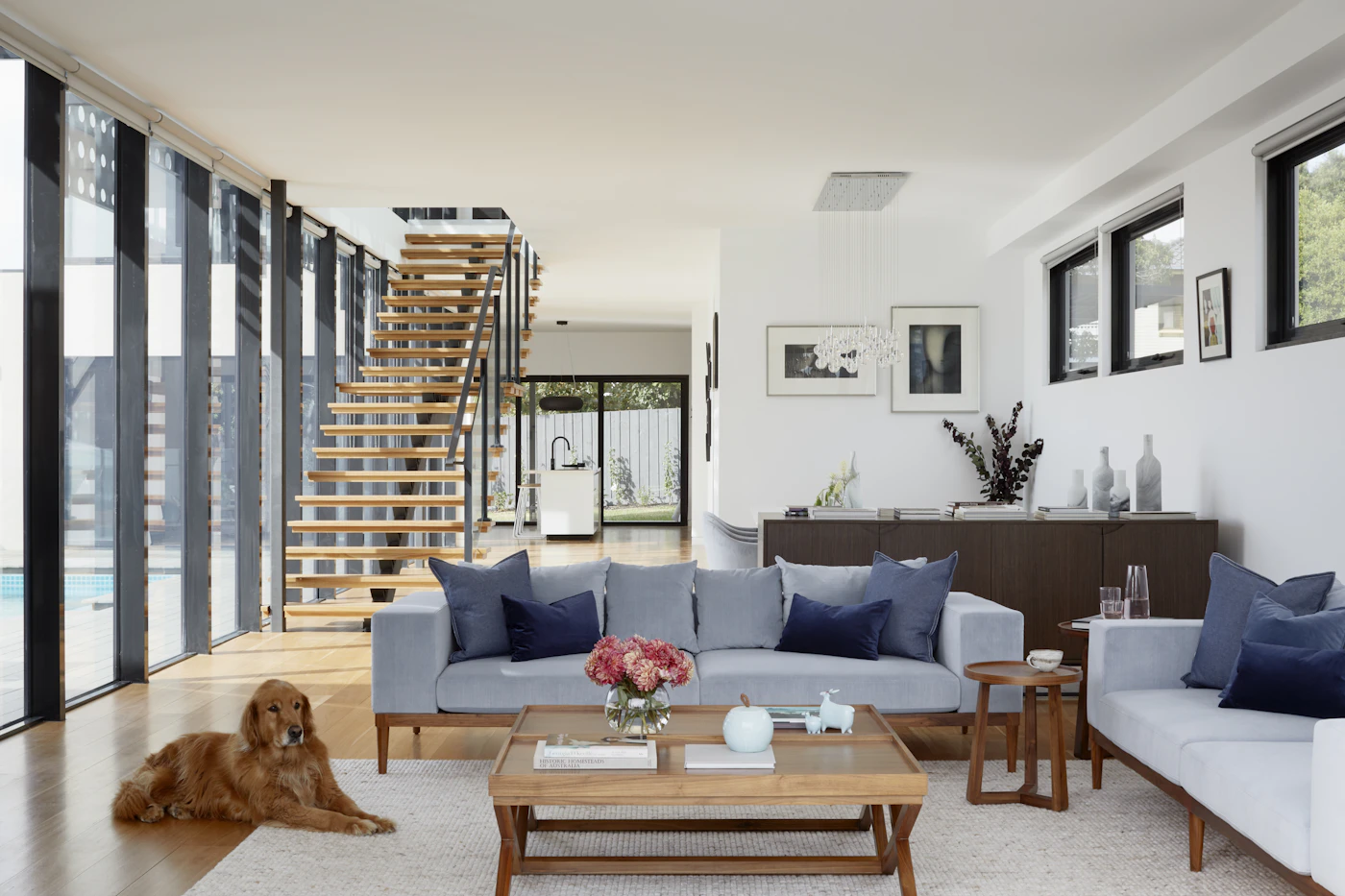 Open living room with a sofa, low coffee table and wooden staircase