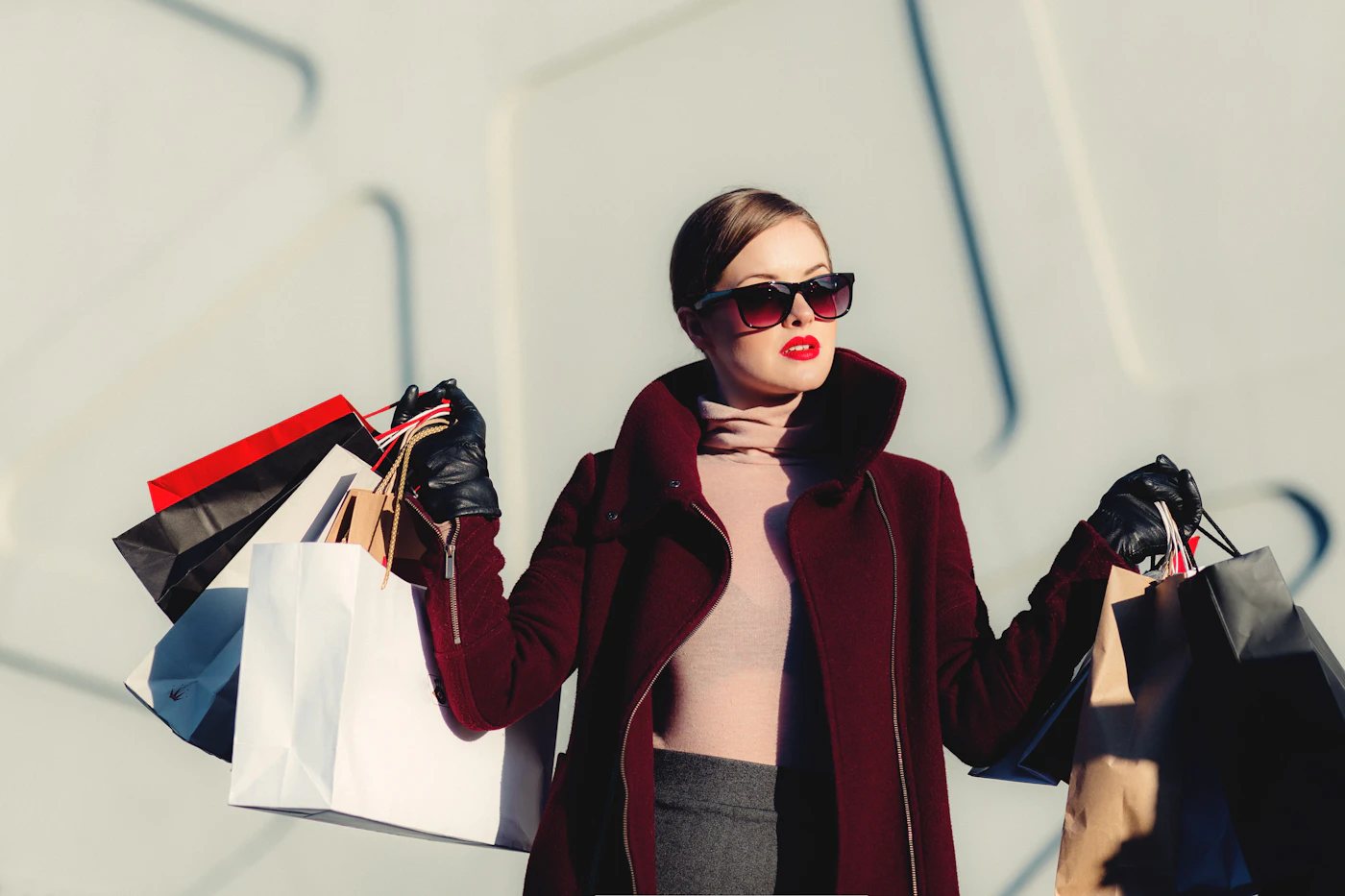 Woman wearing sunglasses and layered outerwear while carrying shopping bags